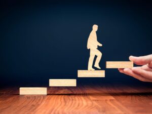 A figure climing steps, representing me coaching businesses and individuals to reach the next level.